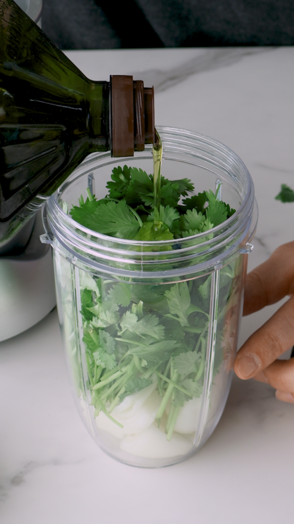 Start by placing an onion, cilantro and into a food processor, pulsing until finely chopped, and then pour this mixture over ground beef. 